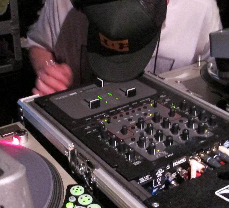 DJ Natural Nate® focused over the mixer with Shure headphones